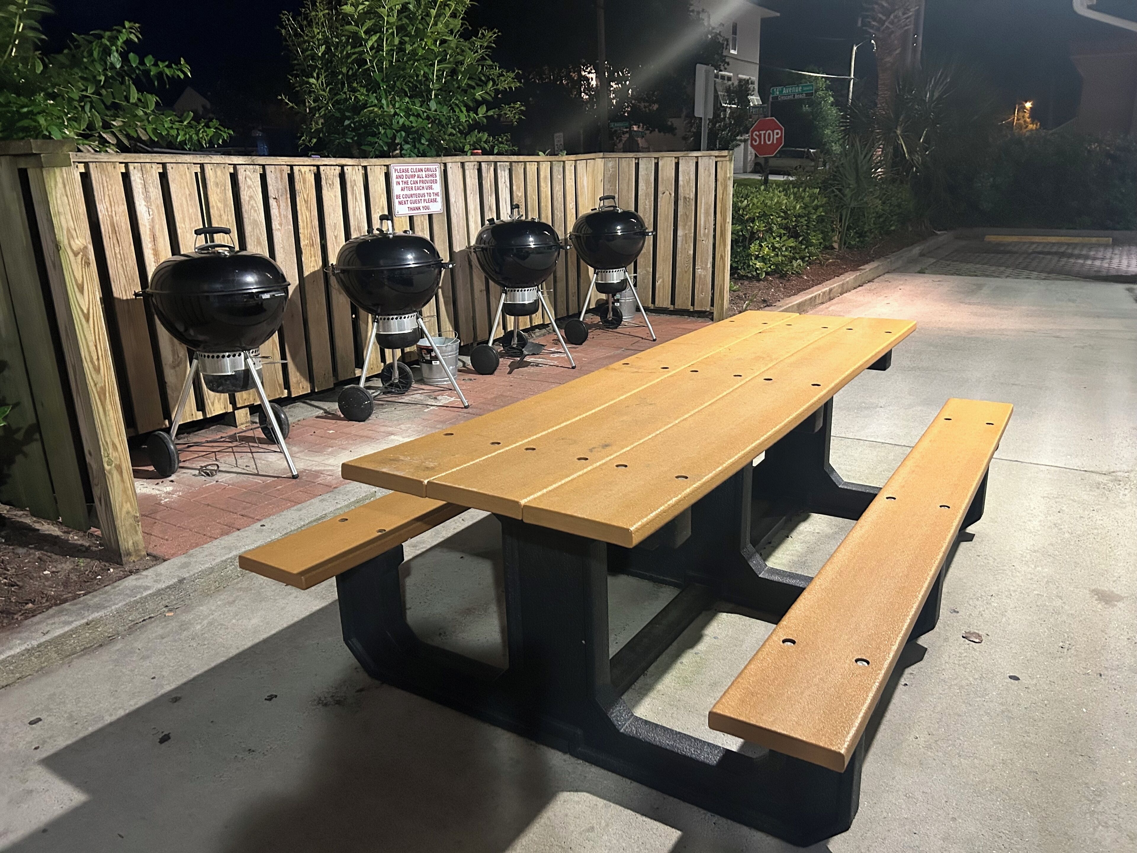 A picnic table with three barbecue grills.