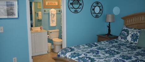 A bedroom with a bed, a nightstand, a lamp, and a wall with two decorative mirrors.