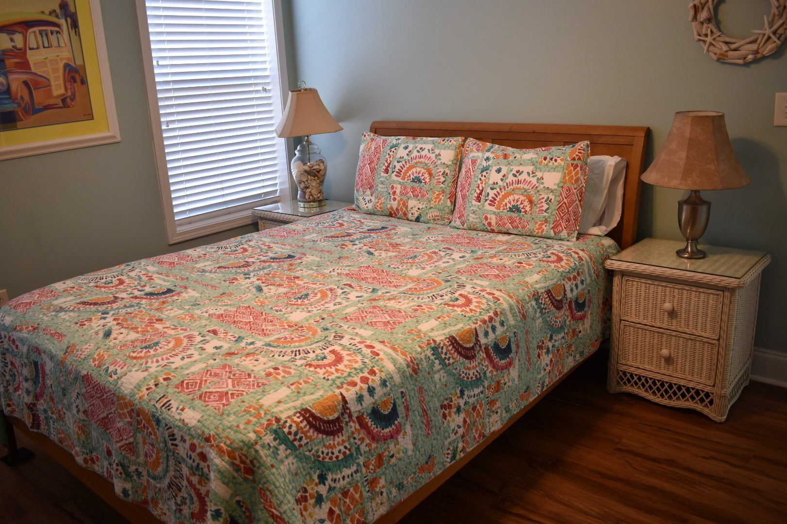 A bedroom with a bed, two bedside tables, a lamp, and a wall decoration.