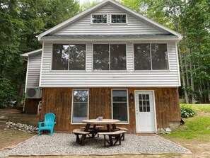 A two-story house with a wooden exterior and a front porch. - Lake Front with Amazing Sunsets on McGrath Pond (Oakland)