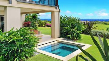 Une maison moderne dotée d’une piscine, d’une végétation luxuriante et offrant une vue sur l’océan.