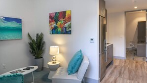 A modern living room with a sofa, a small table, a lamp, and a colorful abstract painting on the wall. - Suite 1 with Kitchenette (St. John)