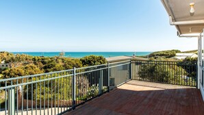 Een balkon met uitzicht op zee en groen.