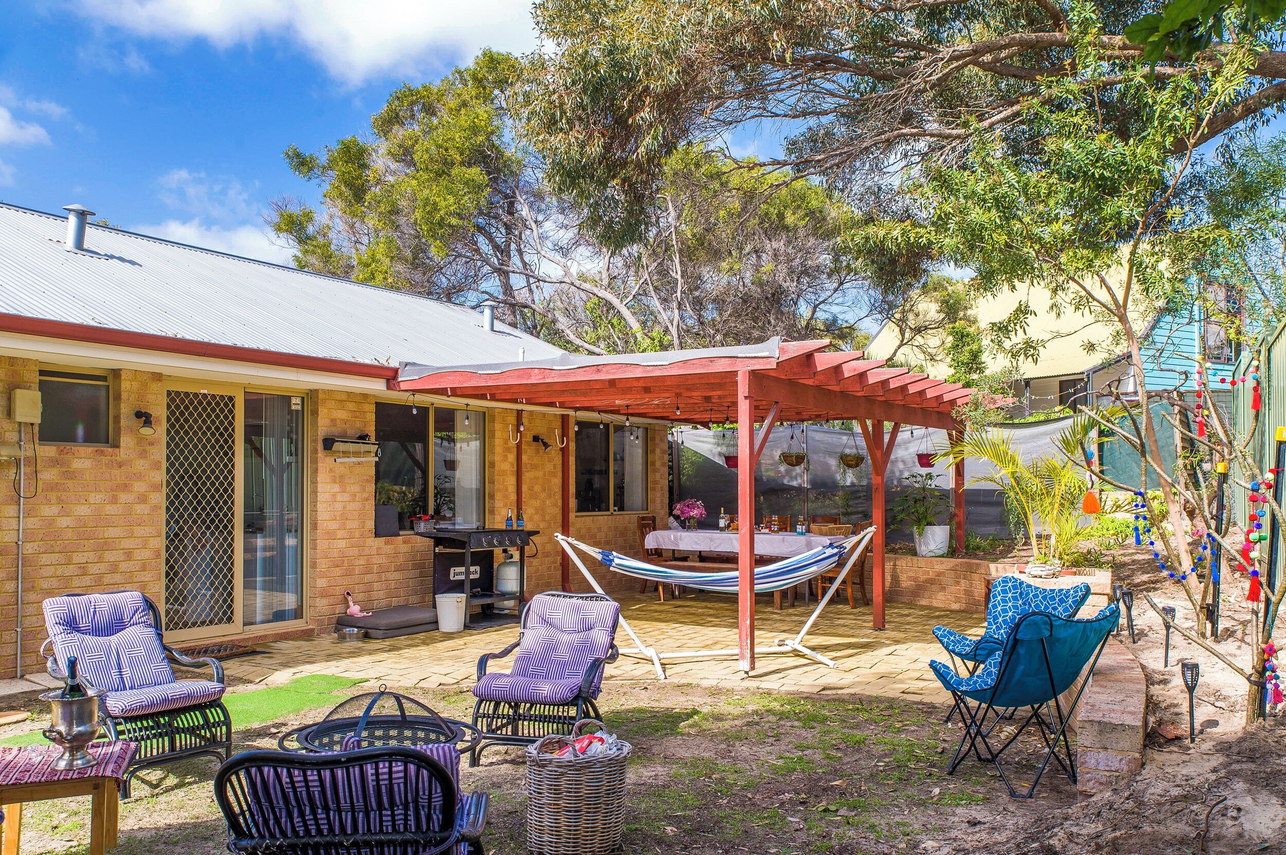 A patio area with a covered seating area, outdoor furniture, and a barbecue grill.