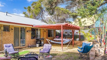 A patio area with a covered seating area, outdoor furniture, and a barbecue grill.