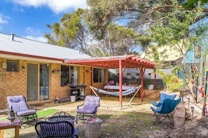 A patio area with a covered seating area, outdoor furniture, and a barbecue grill. - Waves And Moore - Beautifully presented home (Guilderton)
