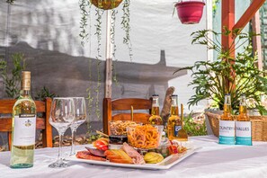 A table set with a bottle of wine, glasses, a fruit platter, and bottles of beer. - Waves And Moore - Beautifully presented home (Guilderton)