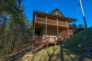Eine zweistöckige Holzhütte mit Balkon und Treppe zum oberen Stockwerk.
