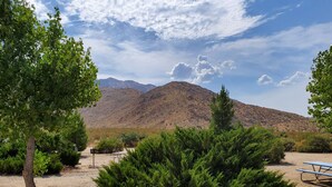 A desert landscape with a mountain in the background, a gravel path, and a picnic table.