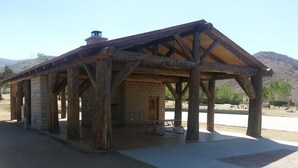 A rustic wooden structure with a pitched roof, brick walls, and a chimney.