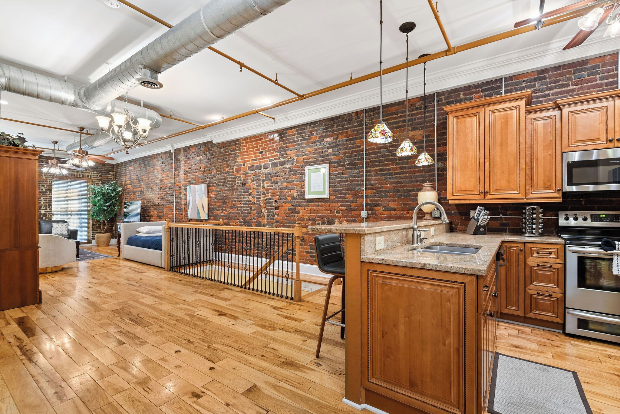 A spacious kitchen with wooden cabinets, a brick wall, and a large island.