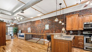A spacious kitchen with wooden cabinets, a brick wall, and a large island. - The Dolly Parton-Printer's Alley- 2 Blocks to Broadway (Nashville)