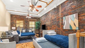A modern room with a brick wall, a ceiling fan, a bed, a sofa, and a TV. - The Dolly Parton-Printer's Alley- 2 Blocks to Broadway (Nashville)