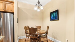A dining area with a round table, wooden chairs, a chandelier, and a stainless steel refrigerator. - The Parton Printer's Alley Nashville- 2 Blocks to Broadway (Nashville)