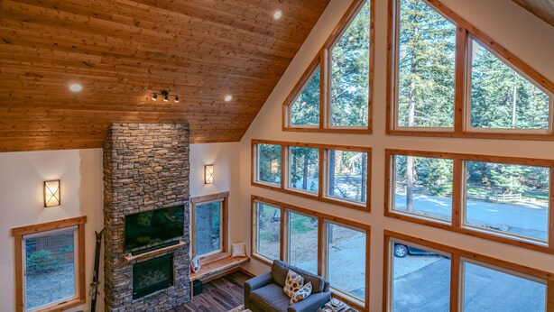 A spacious living area with a stone fireplace, multiple large windows, and a high wooden ceiling. - Mountain Retreat, steps from Skiing, Mountain Biking, and Hiking (Wenatchee)