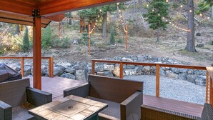 An outdoor patio with wicker furniture and a stone wall backdrop. - Mountain Retreat, steps from Skiing, Mountain Biking, and Hiking (Wenatchee)