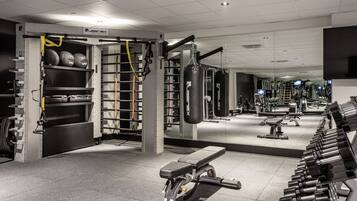 Een fitnessruimte met gewichthefrijsapparatuur, een bank en een bokszak.