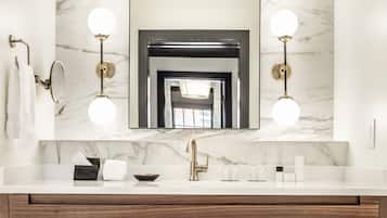 A bathroom with a marble sink, a gold faucet, and two wall-mounted lights.