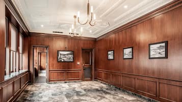 A spacious hallway with wooden paneling, a marble floor, and a chandelier.