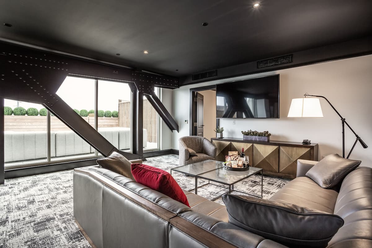 Ein modernes Wohnzimmer mit einer Ledersofa, einem Glastisch und einem großen Flachbildfernseher an der Wand.