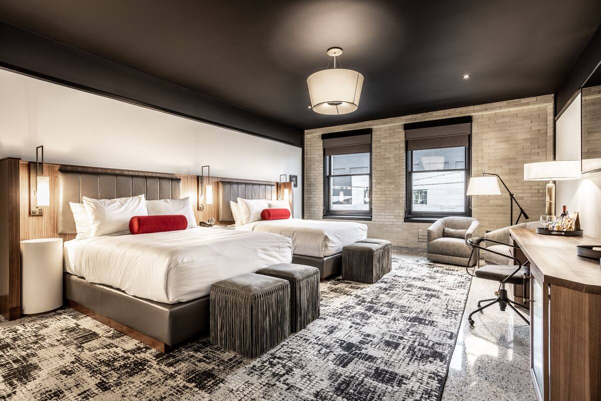 Ein modernes Hotelzimmer mit einem großen Bett, zwei Nachttischen, einem Schreibtisch und einem Sessel.