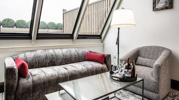 A modern living room with a grey sofa, a matching armchair, a glass coffee table, and a floor lamp.