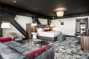 Et moderne hotelværelse med seng, sofa, stol, skrivebord og trappe.