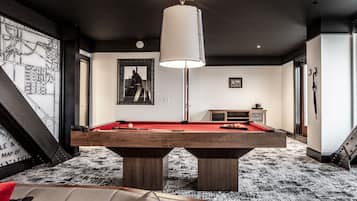 A pool table in a room with a black and white patterned carpet, a red sofa, and a map on the wall.