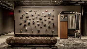 A wall displaying various cameras, a photo booth, and a leather sofa in a modern room.