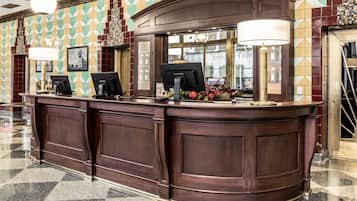 A reception desk with a check-in counter, a computer monitor, and a lamp.