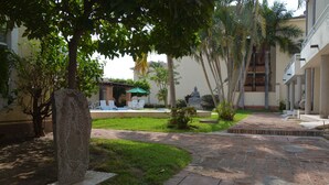 Un patio con un sendero de piedra, una estatua y un edificio con balcón.