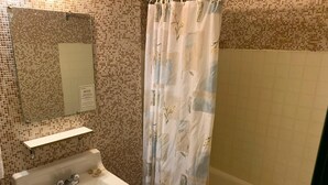 Une salle de bain avec un lavabo, un miroir et un rideau de douche.