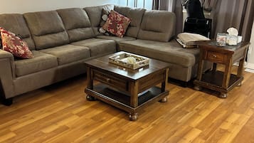 A living room with a sectional sofa, two coffee tables, and a small side table.