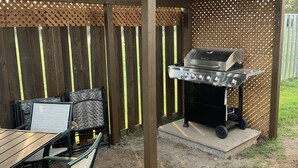 En udendørs patio med grill, bord og stole.