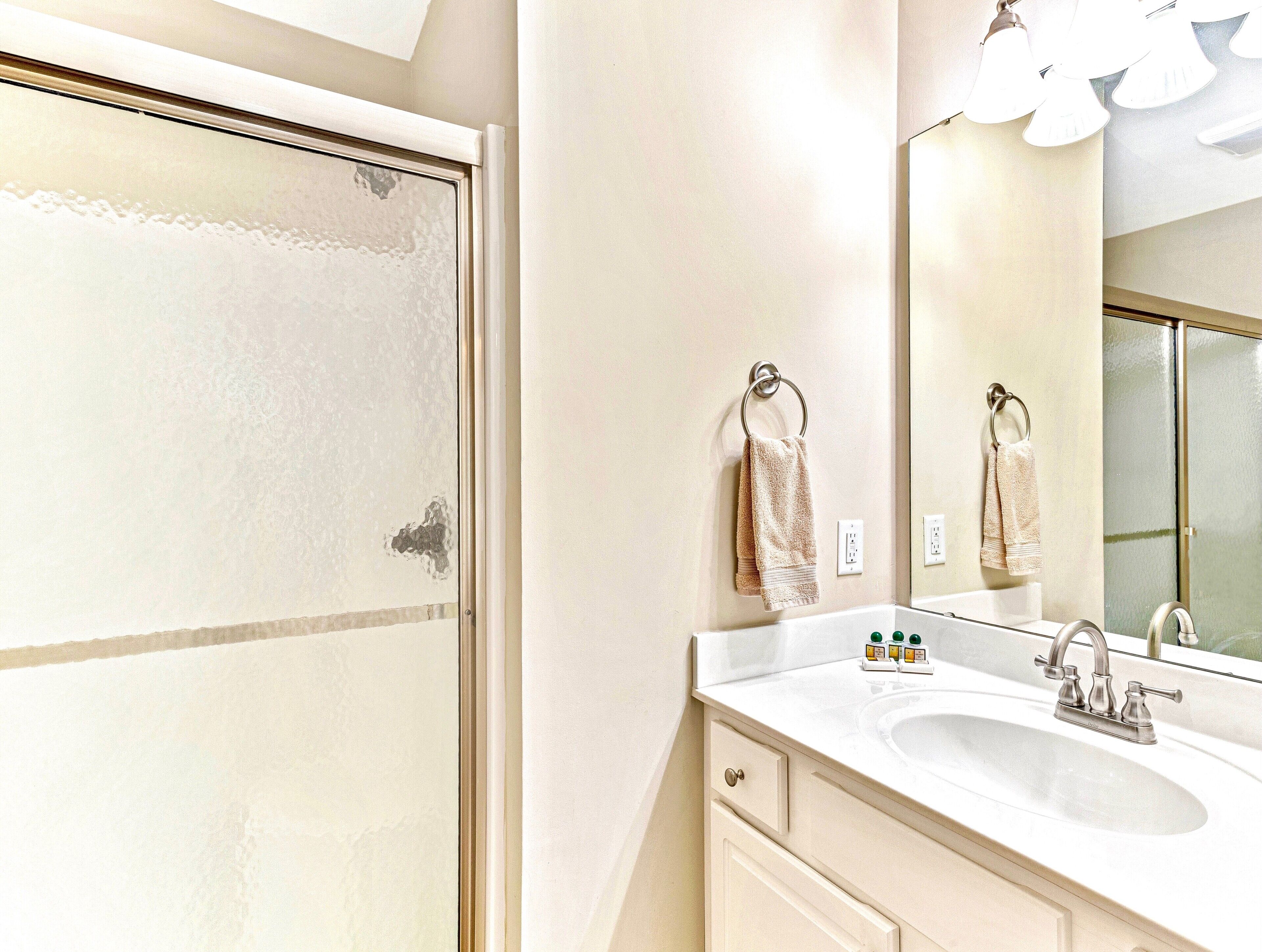 A bathroom with a white sink, a mirror, and two towels hanging on a towel ring.