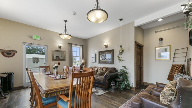 A spacious room with a wooden dining table, multiple chairs, a brown leather sofa, and a patterned rug. - Twisters Bed and Breakfast (Guernsey)