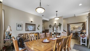 A dining area with a wooden table and chairs, a chandelier, and a sofa. - Twisters Bed and Breakfast (Guernsey)