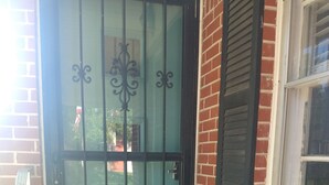 A brick house with a black metal gate and a welcome mat at the entrance. - Mid Century Modern McKenzie (McKenzie)