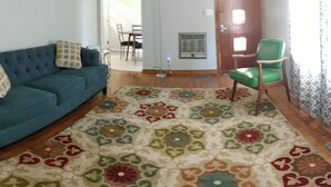 A living room with a blue sofa, a green chair, and a patterned rug. - Mid Century Modern McKenzie (McKenzie)