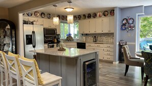 A modern kitchen with white cabinetry, a central island, and pendant lighting.