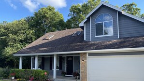 A two-story house with a garage, a covered porch, and a stone accent wall.