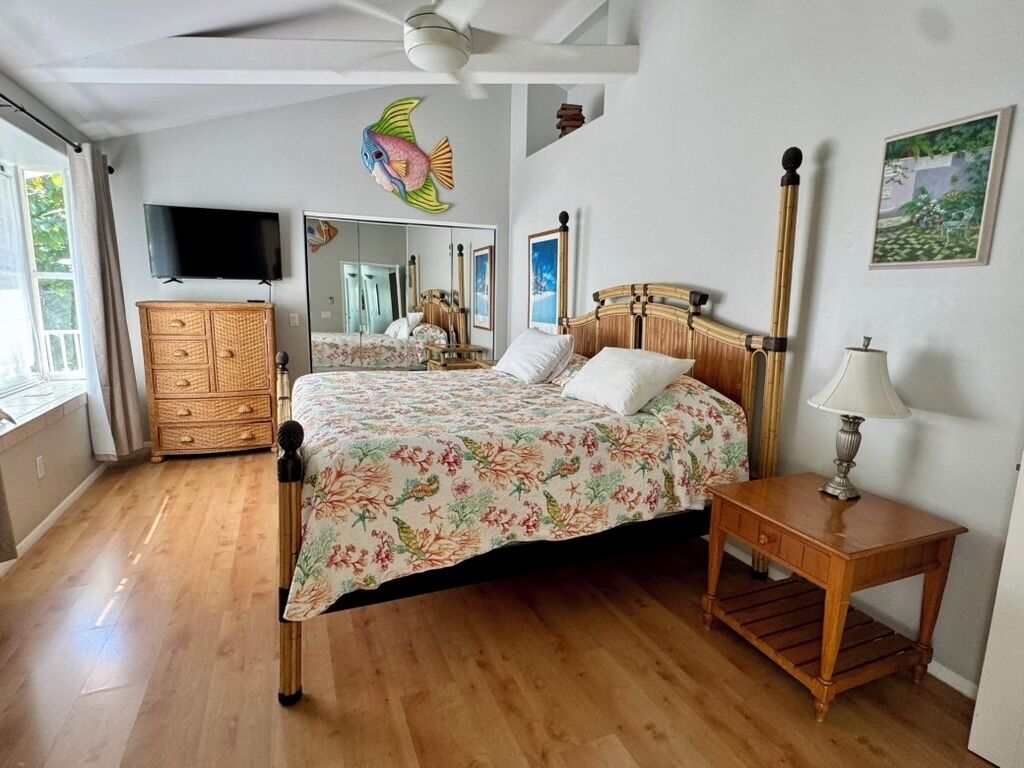 Une chambre à coucher avec un lit en bois, une commode, une télévision et un miroir.