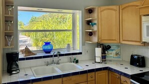 Een keuken met een raam, een spoelbak en houten kastjes.