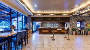 A restaurant with a stone wall, wooden bar, and large windows. - Lake Tahoe | Slopes & Village | Hot Tub | 2BR Villa (South Lake Tahoe)