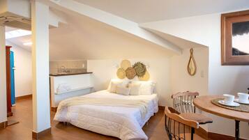 Een slaapkamer met een groot bed, een houten stoel, een tafeltje met kopjes en een wandklok.