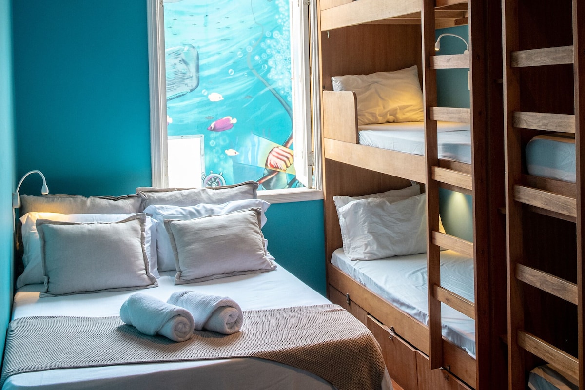 Habitación pequeña con literas, una ventana que da a un barco y un armario de madera.