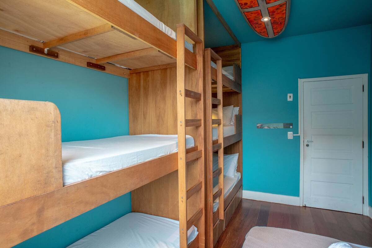 A room with bunk beds, a white door, and teal walls.
