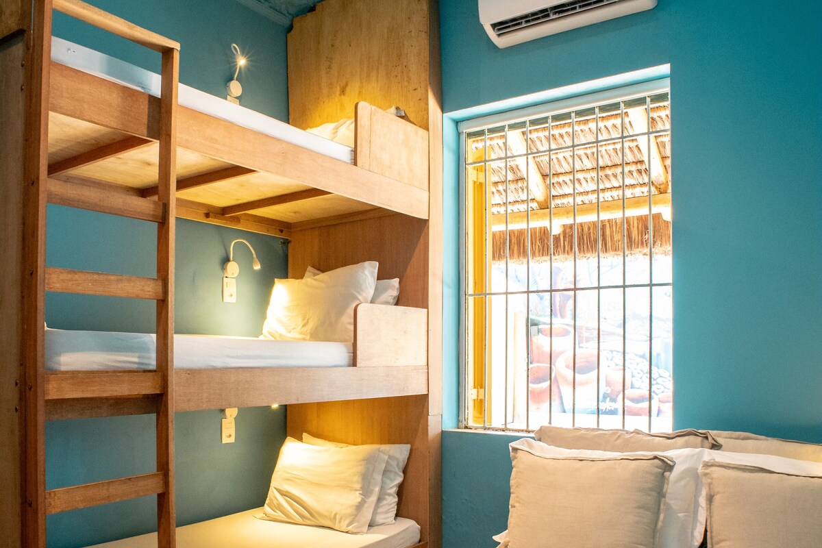 Une chambre avec des lits superposés, une fenêtre avec des barreaux, un climatiseur et un lit avec des serviettes enroulées.