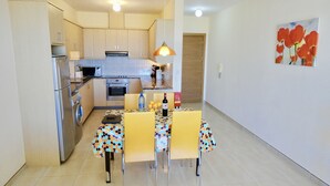 A compact kitchen with modern appliances, a dining area with a polka-dotted tablecloth, and a painting of red flowers on the wall. - Stunning 2-bed Apartment in Poli Crysochous (Polis)