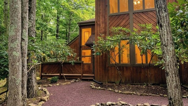 Una cabana de fusta amb un camí de grava, envoltada d'arbres.
